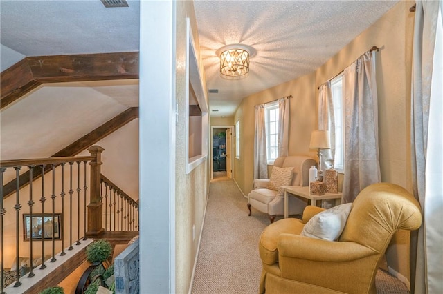 living area featuring a textured ceiling, light colored carpet, and a notable chandelier