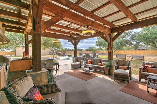 view of patio featuring an outdoor hangout area, ceiling fan, exterior kitchen, a bar, and a fenced in pool