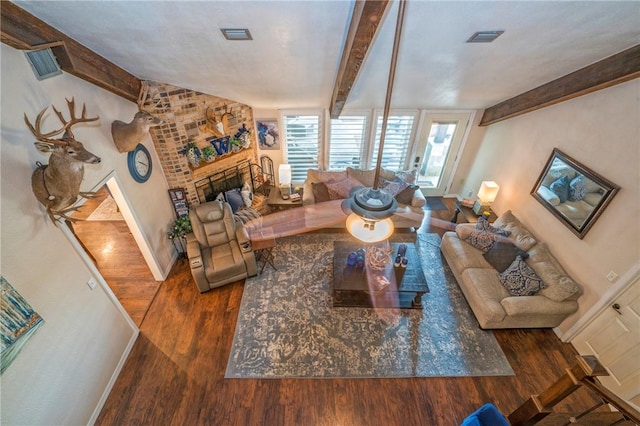 living room with a fireplace, beam ceiling, and dark wood-type flooring