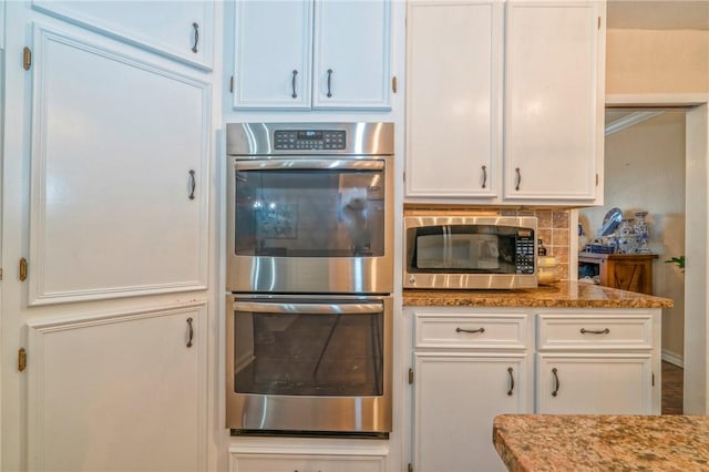 kitchen with light stone countertops, white cabinetry, and stainless steel appliances