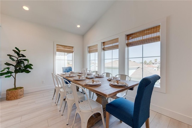 dining space with vaulted ceiling and light wood-type flooring