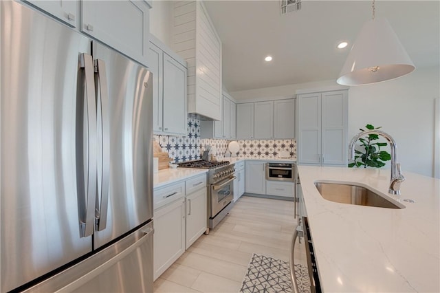 kitchen featuring sink, stainless steel appliances, tasteful backsplash, light stone countertops, and wall chimney exhaust hood