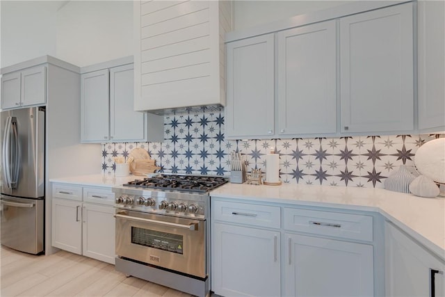 kitchen featuring stainless steel appliances, premium range hood, light hardwood / wood-style floors, and decorative backsplash