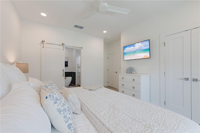 bedroom with ceiling fan, ensuite bathroom, and a barn door