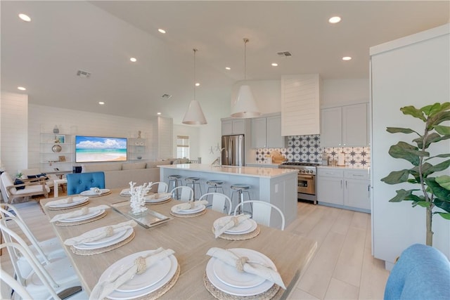 dining room with a high ceiling, sink, and light hardwood / wood-style flooring