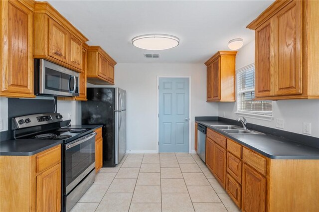 410 Knickerbocker St, Corpus Christi, TX 78418 - kitchen featuring stainless steel appliances, dark countertops, a sink, and light tile patterned flooring