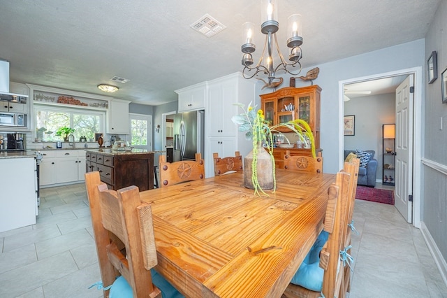 tiled dining space with a chandelier and a textured ceiling