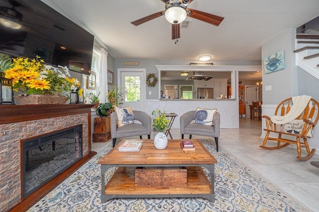 living room with ceiling fan, a fireplace, and light tile patterned floors