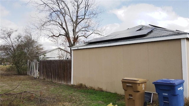 view of side of home featuring roof mounted solar panels and fence