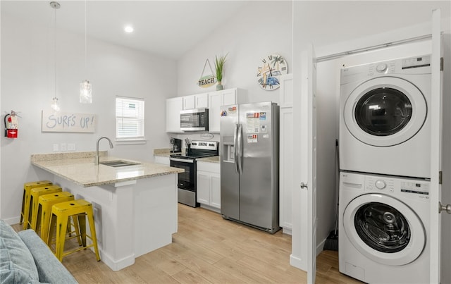 15101 Boca Grandi Dr, Corpus Christi, TX 78418 - kitchen with stacked washer / dryer, a peninsula, a breakfast bar, stainless steel appliances, and a sink