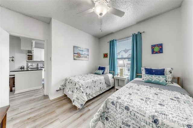 bedroom with a textured ceiling, ceiling fan, and light hardwood / wood-style flooring