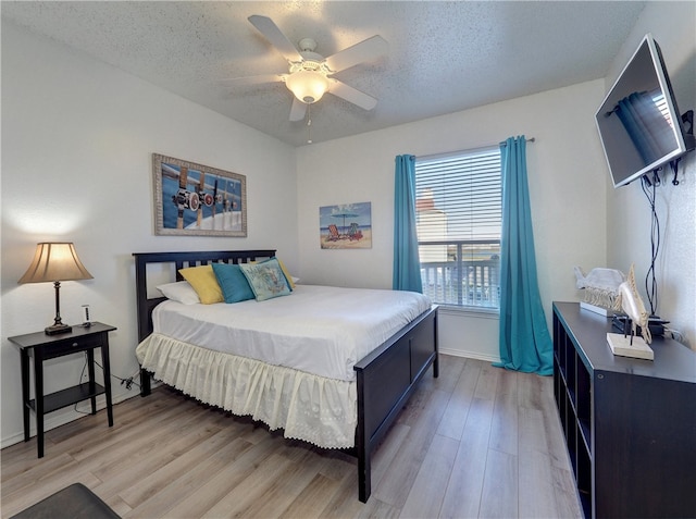 bedroom featuring a textured ceiling, light wood-type flooring, and ceiling fan