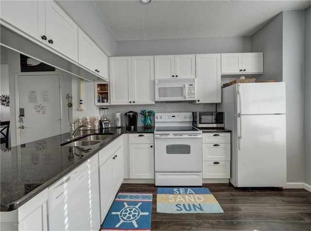 kitchen featuring dark stone counters, white cabinets, sink, dark hardwood / wood-style floors, and white appliances