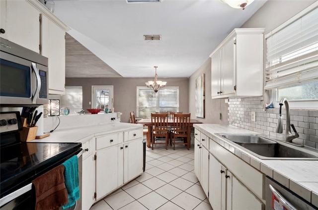 kitchen featuring a wealth of natural light, an inviting chandelier, pendant lighting, and appliances with stainless steel finishes