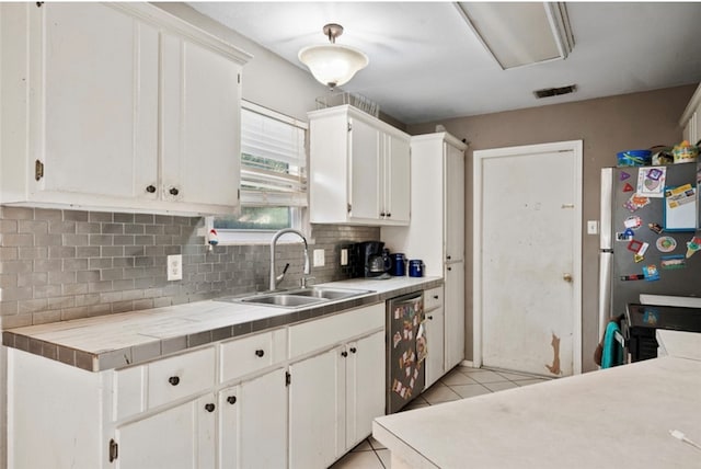 kitchen with tasteful backsplash, stainless steel appliances, sink, light tile patterned floors, and white cabinetry