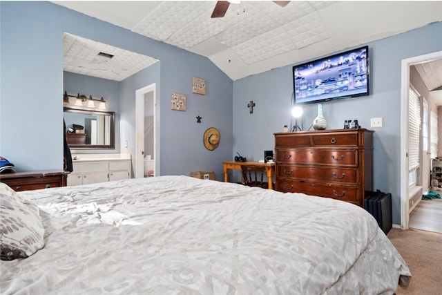 carpeted bedroom with ceiling fan, lofted ceiling, and ensuite bath