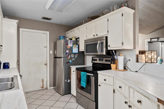 kitchen featuring white cabinetry, sink, light tile patterned floors, and appliances with stainless steel finishes