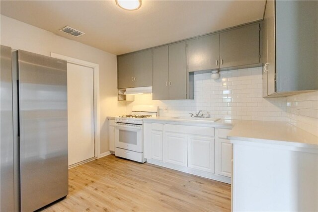 4338 Cottage St, Corpus Christi, TX 78415 - kitchen featuring freestanding refrigerator, white range with gas cooktop, a sink, under cabinet range hood, and light countertops
