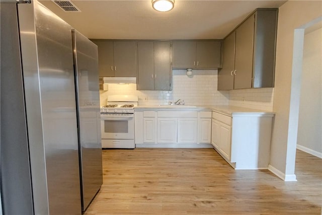4338 Cottage St, Corpus Christi, TX 78415 - kitchen featuring freestanding refrigerator, white gas range oven, under cabinet range hood, light countertops, and light wood-type flooring