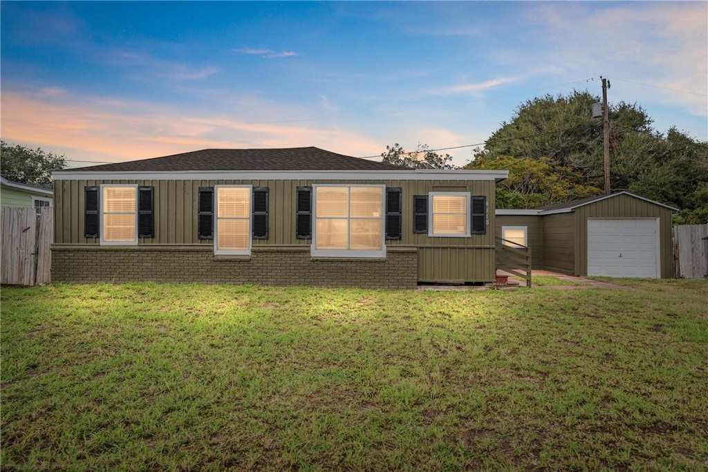 back house at dusk featuring an outbuilding, a garage, and a yard