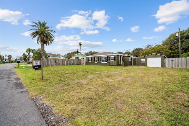 view of front of property featuring a garage, a front yard, and an outbuilding