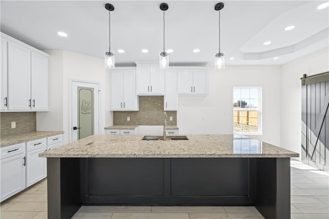 kitchen featuring a kitchen island with sink, white cabinets, a sink, and recessed lighting