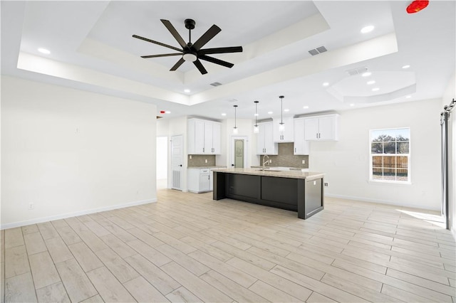 kitchen with a sink, visible vents, light countertops, backsplash, and a raised ceiling