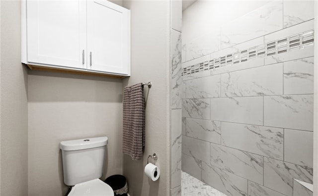 bathroom with toilet and a tile shower