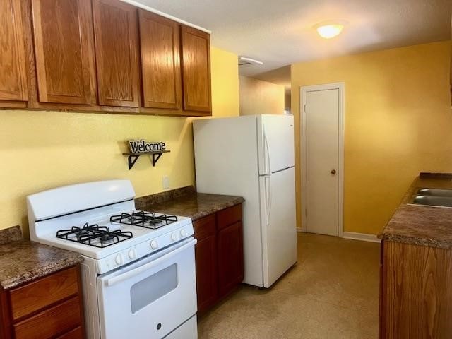 502 S Stephenson St, Beeville, TX 78102 - kitchen featuring white appliances, light colored carpet, brown cabinets, and dark countertops