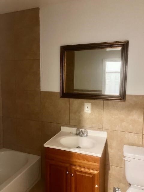 502 S Stephenson St, Beeville, TX 78102 - bathroom featuring tile walls, vanity, and a tub