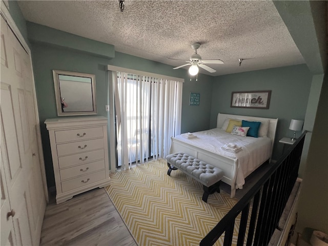 bedroom with a closet, light wood-type flooring, a textured ceiling, and ceiling fan