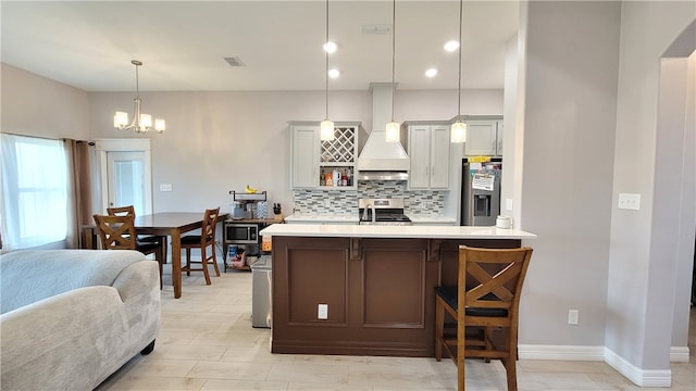 kitchen featuring a kitchen bar, an inviting chandelier, decorative backsplash, hanging light fixtures, and appliances with stainless steel finishes