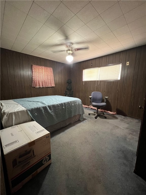 carpeted bedroom with wood walls and ceiling fan