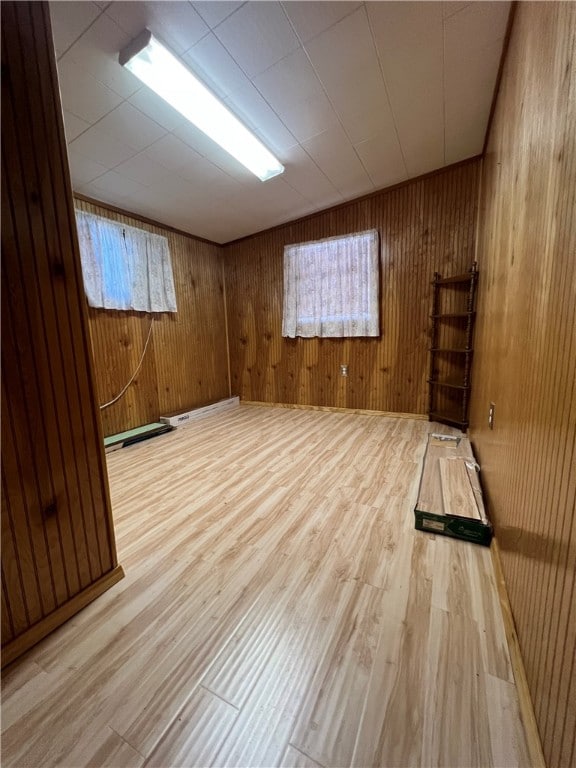 unfurnished room featuring light hardwood / wood-style flooring, wooden walls, and plenty of natural light