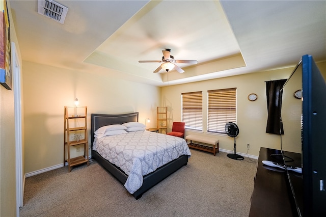 bedroom with a tray ceiling, carpet, and ceiling fan