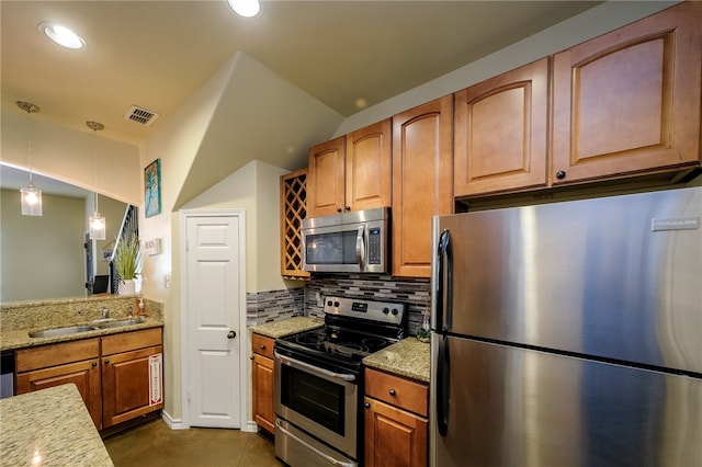 kitchen with light stone countertops, appliances with stainless steel finishes, decorative light fixtures, and backsplash