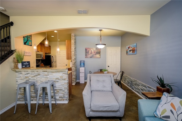 interior space with fridge, light stone countertops, kitchen peninsula, and decorative light fixtures