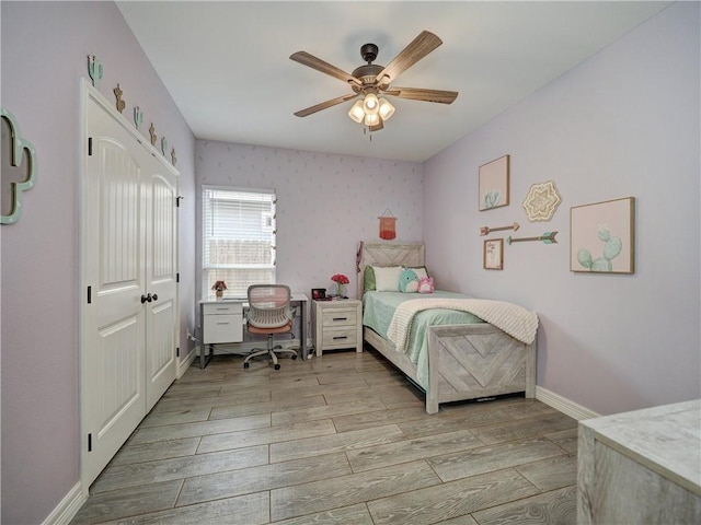 bedroom featuring light wood-type flooring, a ceiling fan, baseboards, and a closet