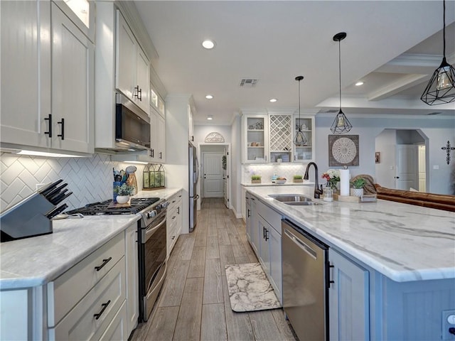 kitchen with visible vents, wood tiled floor, stainless steel appliances, white cabinetry, and a sink