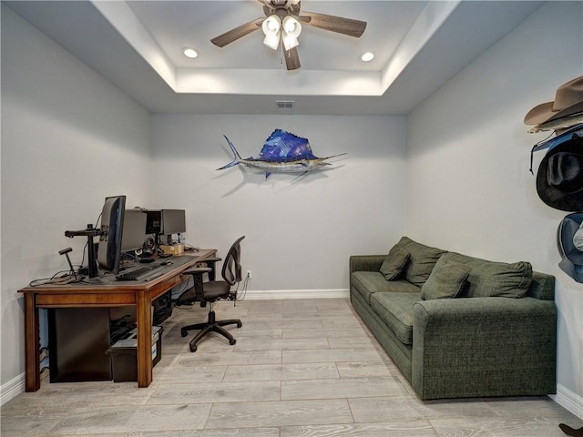 office space featuring a tray ceiling, visible vents, baseboards, and wood tiled floor