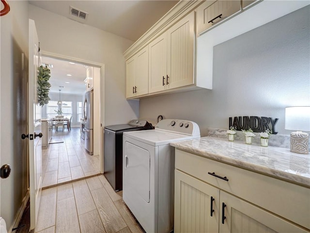 laundry room featuring wood tiled floor, cabinet space, visible vents, and separate washer and dryer