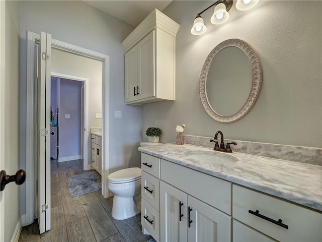 bathroom featuring wood tiled floor, baseboards, vanity, and toilet