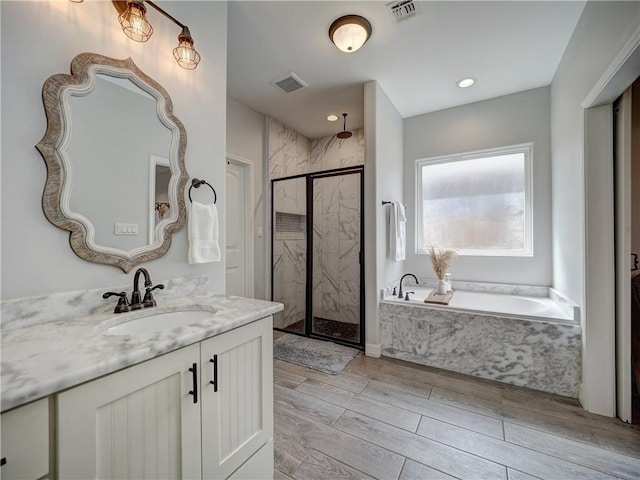 full bath featuring a marble finish shower, visible vents, a garden tub, wood tiled floor, and vanity