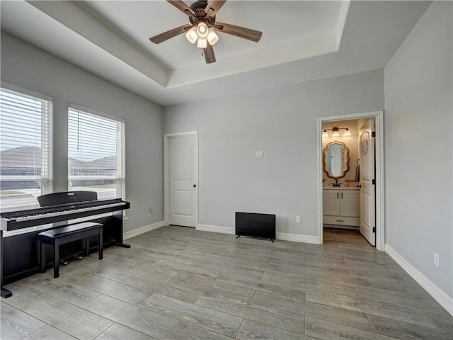 living area with a tray ceiling and baseboards