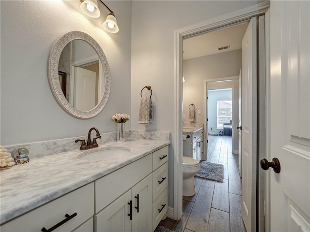 bathroom with visible vents, vanity, toilet, and wood finished floors