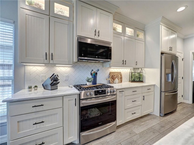 kitchen with light wood finished floors, tasteful backsplash, and stainless steel appliances