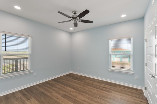 spare room with dark wood finished floors, a wealth of natural light, and baseboards
