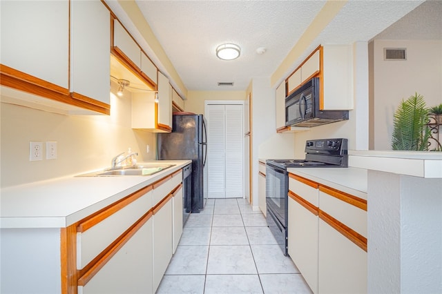 kitchen featuring black appliances, white cabinetry, sink, and light tile patterned floors