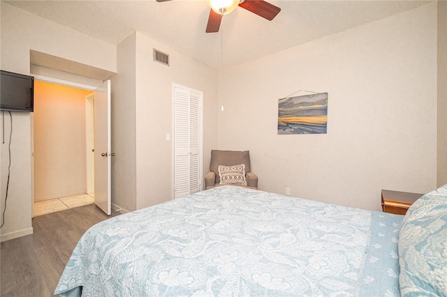 bedroom with dark hardwood / wood-style flooring, a closet, and ceiling fan