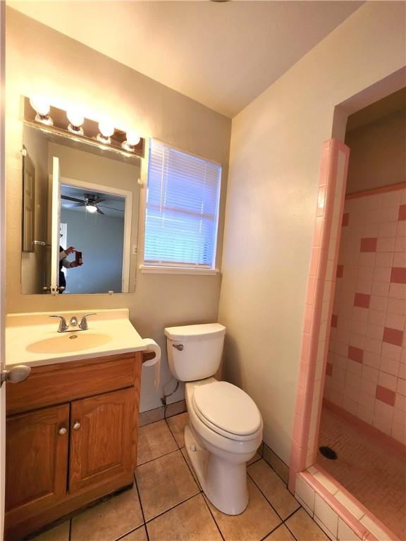 bathroom featuring tile patterned floors, toilet, vanity, and a tile shower